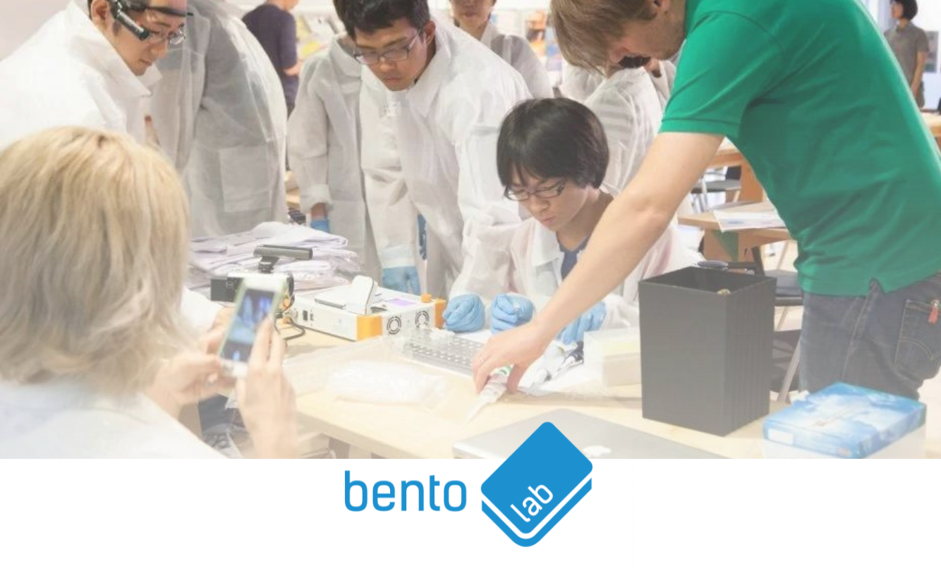 Trainees in lab coats using Bento Lab portable DNA analysis kits at a hands-on workshop, with the Bento Lab logo